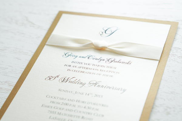 alt=“Classic 50th Wedding Anniversary invitation features an ivory pearlescent shimmer card stock on a gold leaf pearlescent shimmer card stock, an elegant monogram and jewel detail and is finished with a rich ivory knotted ribbon”