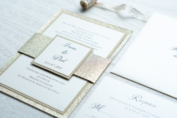 alt="Luxurious wedding invitation features an ivory pearlescent shimmer card stock layered onto gold pearlescent shimmer and glitter stock layers and a coordinating belly band with couple's names and wedding date"