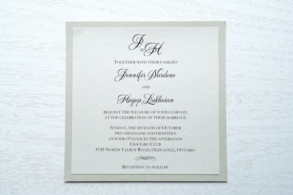 alt="Classic square wedding invitation features an ivory pearlescent shimmer card stock on a champagne gold pearlescent shimmer stock, black font and a monogram/pearl detail"