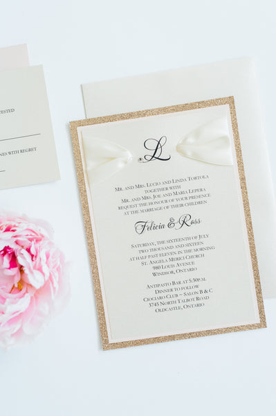 alt="Classic rose gold and blush pink wedding invitation with monogram and jewel detail, glitter card stock and ivory satin ribbon"