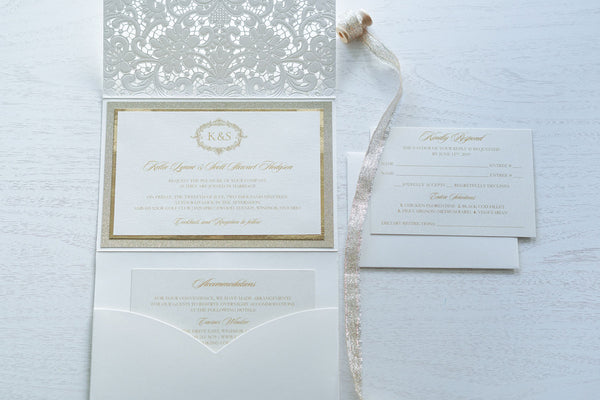 alt="Graceful ivory pearlescent shimmer laser cut pocket fold wedding invitation features an ivory pearlescent shimmer stock on gold mirror and glitter stock layers and encompasses a regal gold frame design with monogram, script font and jewel details"