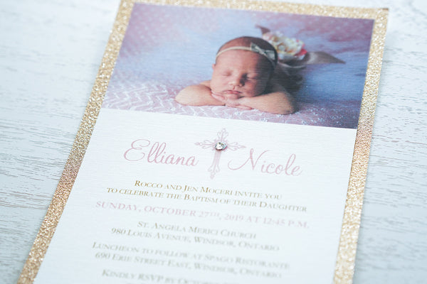 alt="Sweet glitter Baptism photo invitation features an ivory linen matte card stock on a rose gold glitter stock, an elegant pink cross and jewel detail with the honouree’s name and baby's photo"