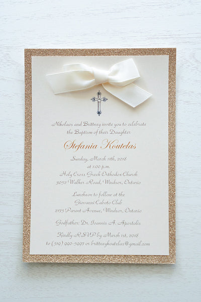 alt=“Classic embellished Baptism invitation features a soft pink pearlescent shimmer card stock on a rose gold glitter card stock, an elegant cross and jewel detail finished with a rich ivory satin ribbon bow”