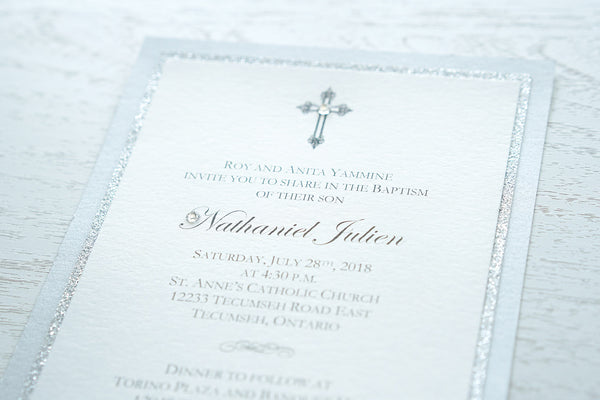 alt=“Elegant layered Baptism invitation features a white pearlescent shimmer card stock on silver glitter and silver pearlescent shimmer card stock layers finished with an elegant cross and jewel detail”
