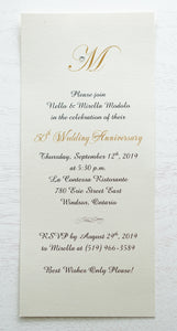 alt=“Simplistic 50th Wedding Anniversary invitation features an ivory pearlescent shimmer card stock and an elegant gold monogram and jewel detail”