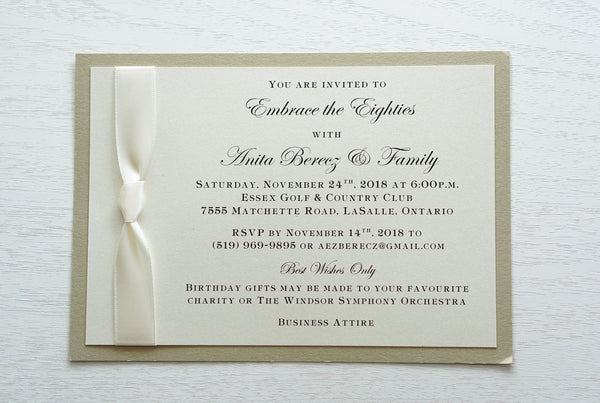 alt="Classic birthday invitation features an ivory pearlescent shimmer card stock on a champagne gold stock and a rich ivory satin knotted ribbon detail"