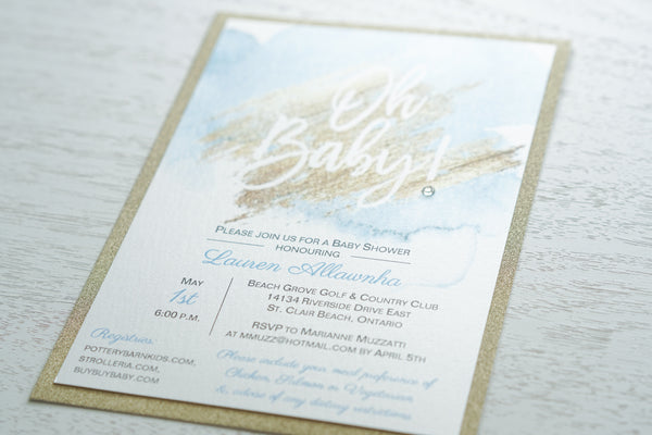 “Trendy baby shower invitation features quartz pearlescent shimmer and gold glitter card stock layers and a blue and gold watercolour design with a sweet “Oh Baby!” sentiment and jewel detail”