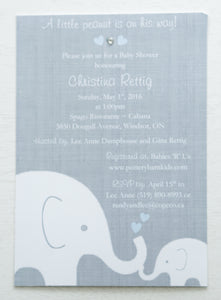 alt=“Sweet baby shower invitation features a grey background print and a white baby and mama elephant image with blue hearts. Heart colour can be customized to suit gender”