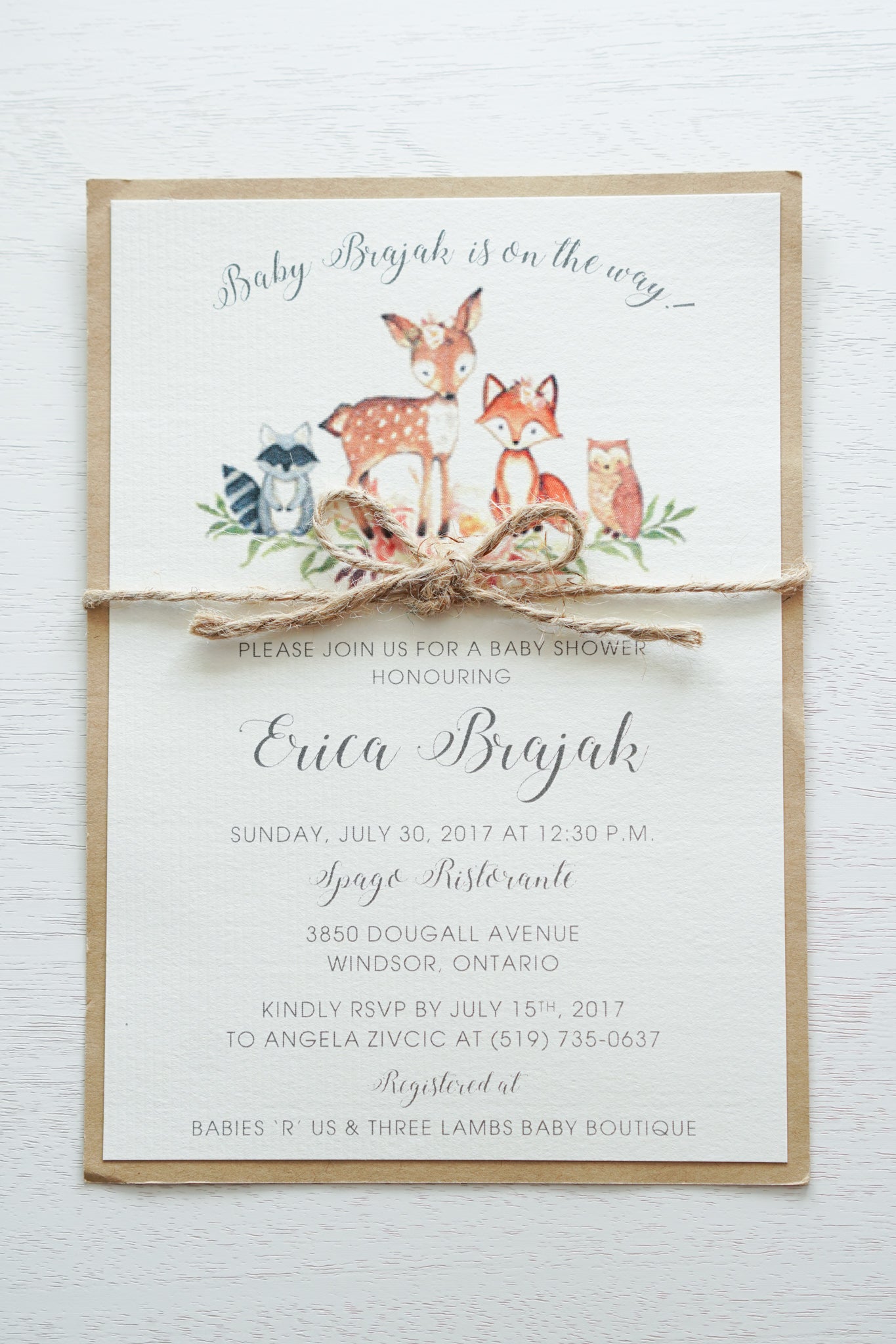 alt=“Rustic gender neutral baby shower invitation features ivory laid and kraft card stock, printed woodland animals and is finished with a twine bow detail”