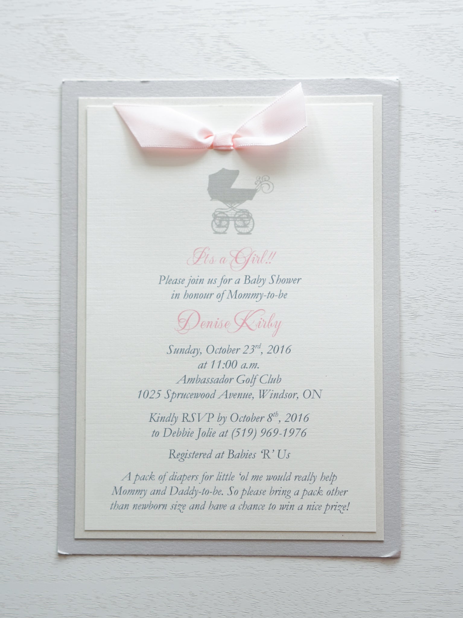 alt=“Classic invitation features ivory linen matte card stock on ivory pearlescent shimmer and grey pearlescent shimmer card stock with a grey pram and a rich pink satin ribbon bow detail”