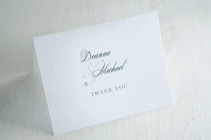 alt="Folded thank you card features a white or ivory pearlescent shimmer card stock, personalized thank you message and a monogram/jewel detail"