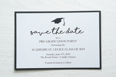 alt="Modern graduation party invitation features a white pearlescent shimmer stock on a matte black card stock, a black grad cap and jewel detail and a modern script font"