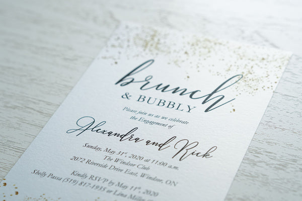 alt="Sparkling confetti engagement party invitation features a white pearlescent shimmer card stock with gold confetti and a modern script font"