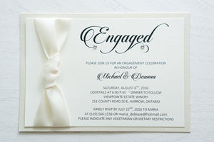 alt="Elegant engagement party invitation features an ivory linen stock on an ivory pearlescent shimmer card stock, a rich ivory ribbon knotted bow and Engaged in script with a jewel detail"