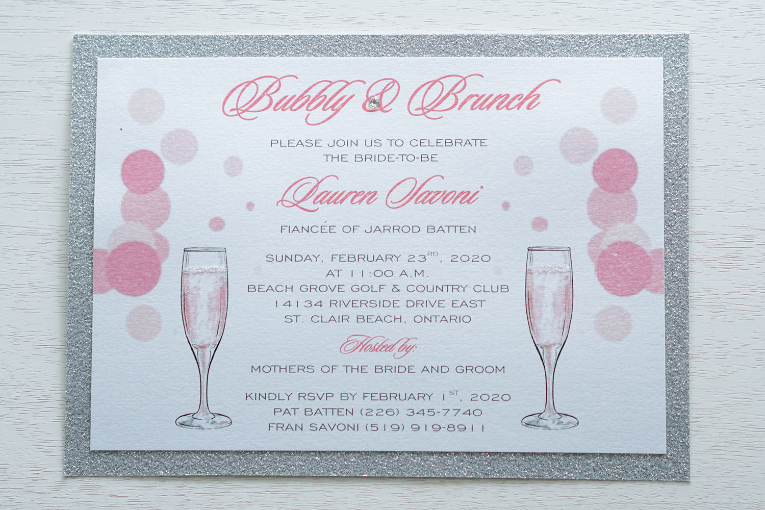 alt="Sparkling glitter Bridal Shower invitation features a white pearlescent shimmer card stock on a silver glitter stock, a champagne flutes and bubbly design, jewel detail and glitter sparkle to finish it off"