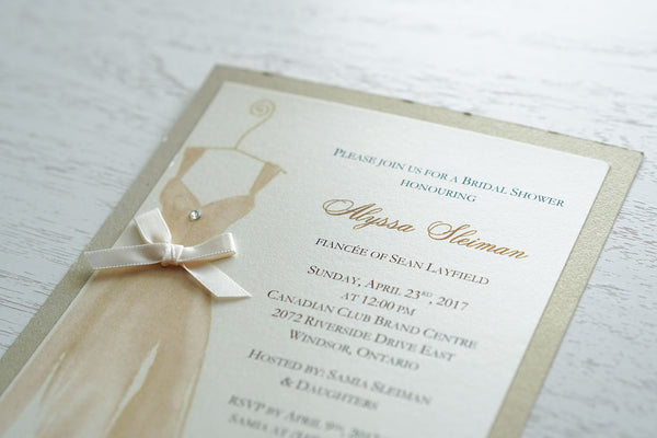 alt="Elegant Bridal Shower invitation features an ivory pearlescent shimmer card stock on a gold leaf pearlescent shimmer stock, a beautiful gold watercolour wedding dress design complete with jewel detail and a rich satin ivory ribbon bow to finish it off"