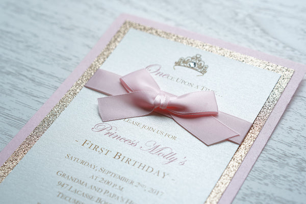 alt="Classic birthday party invitation features an ivory pearlescent shimmer stock on rose gold glitter and pink pearlescent shimmer card stock layers, an elegant gold crown and jewel detail and is finished together with a rich pink ribbon bow"
