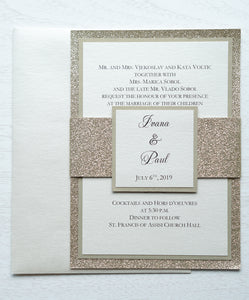 alt="Luxurious wedding invitation features an ivory pearlescent shimmer card stock layered onto gold pearlescent shimmer and glitter stock layers and a coordinating belly band with couple's names and wedding date"