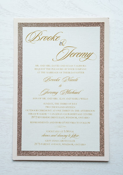 alt="Elegant wedding invitation features an ivory linen pearlescent shimmer card stock layered onto rose gold glitter and blush pink pearlescent shimmer stock layers, a jewel detail and a modern script font"