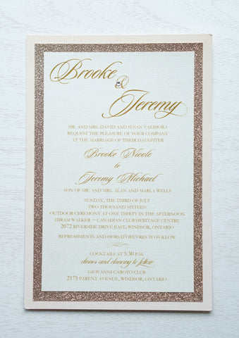 alt="Elegant wedding invitation features an ivory linen pearlescent shimmer card stock layered onto rose gold glitter and blush pink pearlescent shimmer stock layers, a jewel detail and a modern script font"