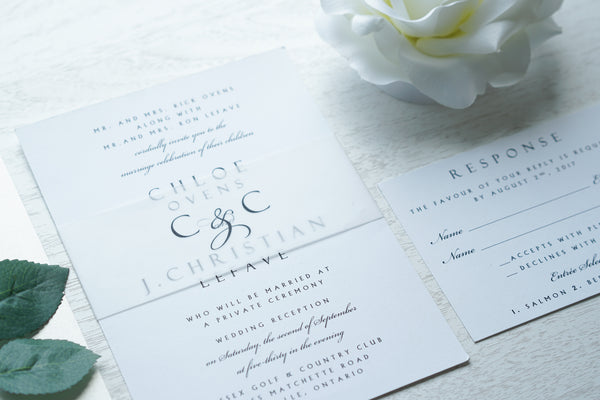 alt="Modern wedding invitation features a white matte card stock, black script and block font and a vellum belly band with monogram detail"