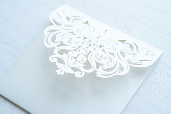 alt="Elegant ivory pearlescent shimmer laser cut square pocket fold wedding invitation features an ivory pearlescent shimmer stock on gold mirror and glitter stock layers and a jewel detail"