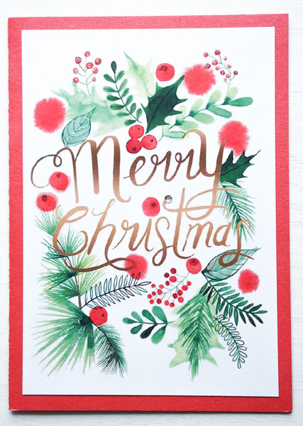 alt="This festive Christmas card features a white and red pearlescent shimmer card stock, watercolour greenery and is finished with glitter dust and a jewel detail"