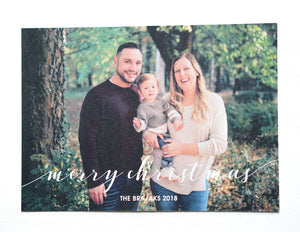 alt="This classic photo card features an ivory pearlescent card stock, “Merry Christmas” printed with family name and year as well as a photo of your choice on the front. On the back two more photos of your choice can be displayed with a greeting"
