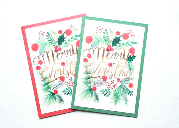 alt="This festive Christmas card features a white and red or green pearlescent shimmer card stock, watercolour greenery and is finished with glitter dust and a jewel detail"