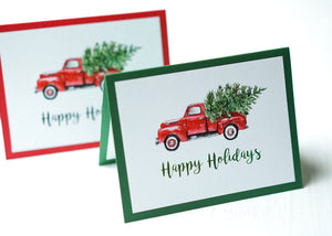 alt="This vintage card features a white matte card stock on a green or red pearlescent shimmer card stock, a vintage red truck with tree and glitter dust and “Happy Holidays” or "Merry Christmas” in a black or green script font"