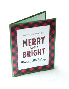 alt=“This modern rustic style card features a white matte card stock on a green pearlescent shimmer card stock, a buffalo plaid pattern and “May your days be merry and bright” printed sentiment with “Happy Holidays” or Merry Christmas” in a script font”