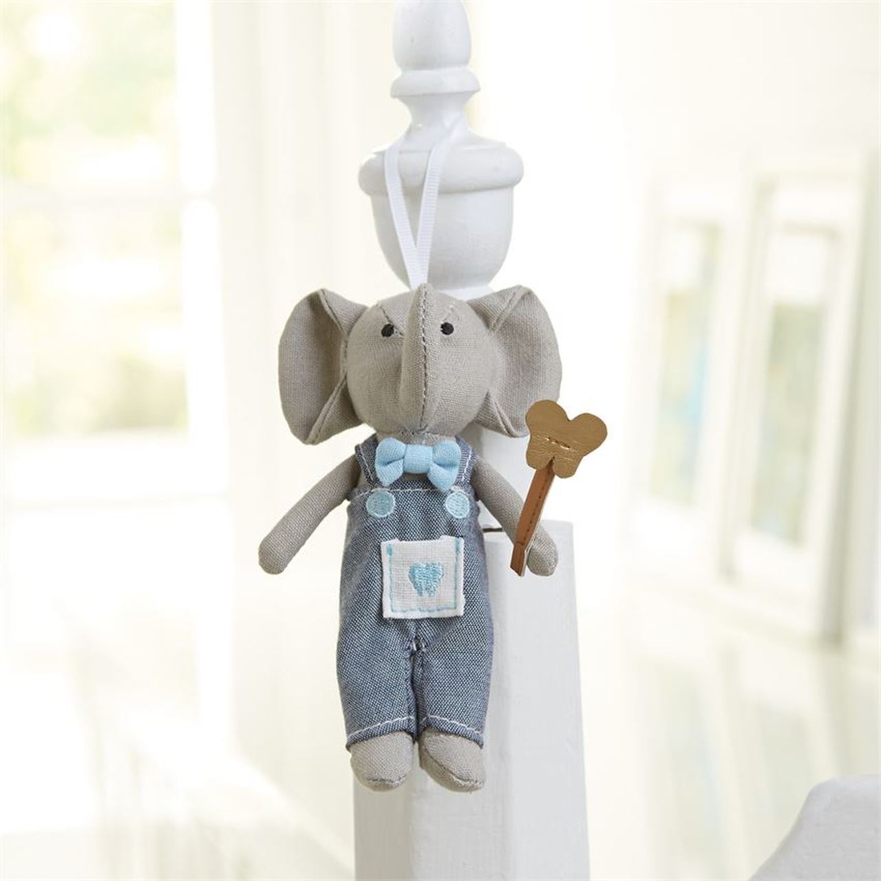 alt=“Blue and grey Tooth Fairy elephant pocket buddy doll complete with fairy wand, bowtie and chambray bib overalls features a special front pocket to place a lost tooth and hangs from a grosgrain ribbon, comes packaged in corrugated gift box”