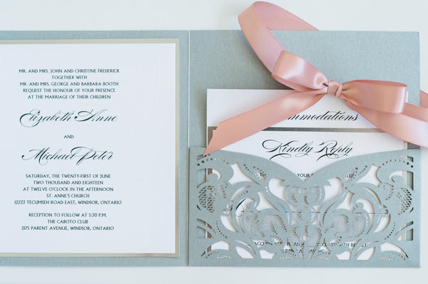alt="Elegant silver pearlescent shimmer laser cut square pocket fold wedding invitation features a white pearlescent shimmer stock on a silver mirror stock and is tied together with a rich pink satin ribbon bow"