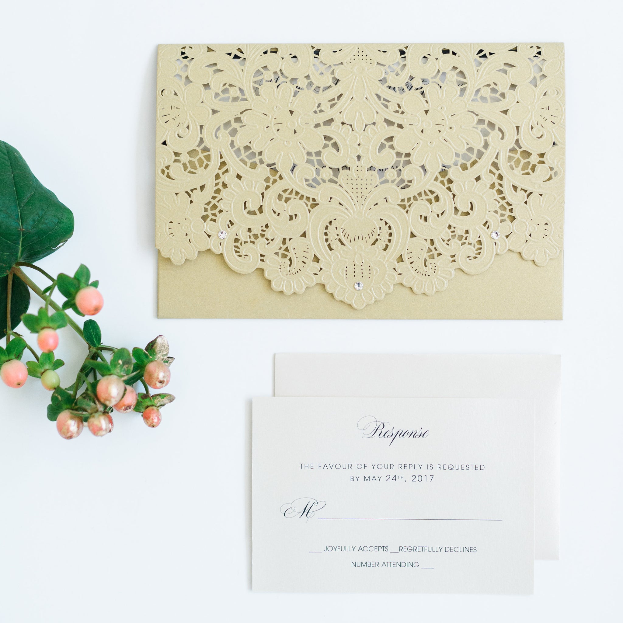 alt="Graceful gold pearlescent shimmer laser cut  pocket wedding invitation features an ivory pearlescent shimmer stock on a black matte stock insert and is finished with jewel details"
