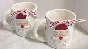 alt="White ceramic mug with Santa with button nose and HO HO HO sentiment on hat. Features red stitches around the top rim, button details on back and is finished with a festive ribbon"
